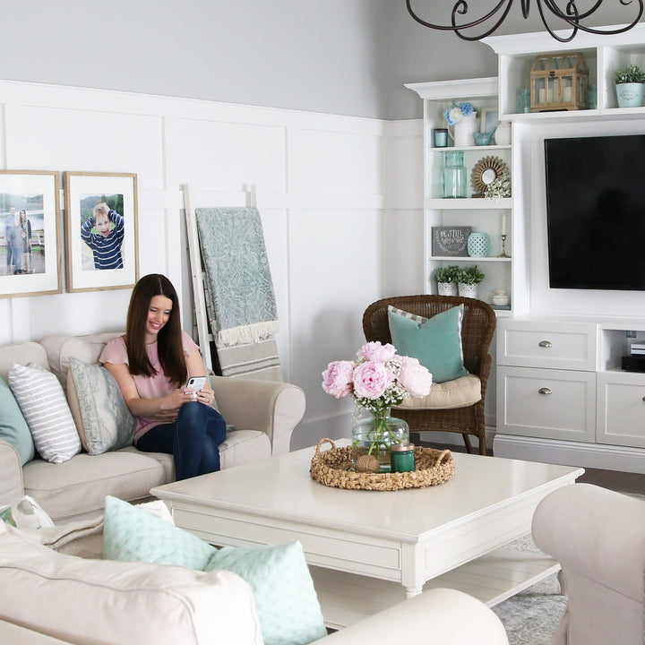 Woman sitting on a couch in the living room, looking at Evernote on her phone, accessing documents for going paperless