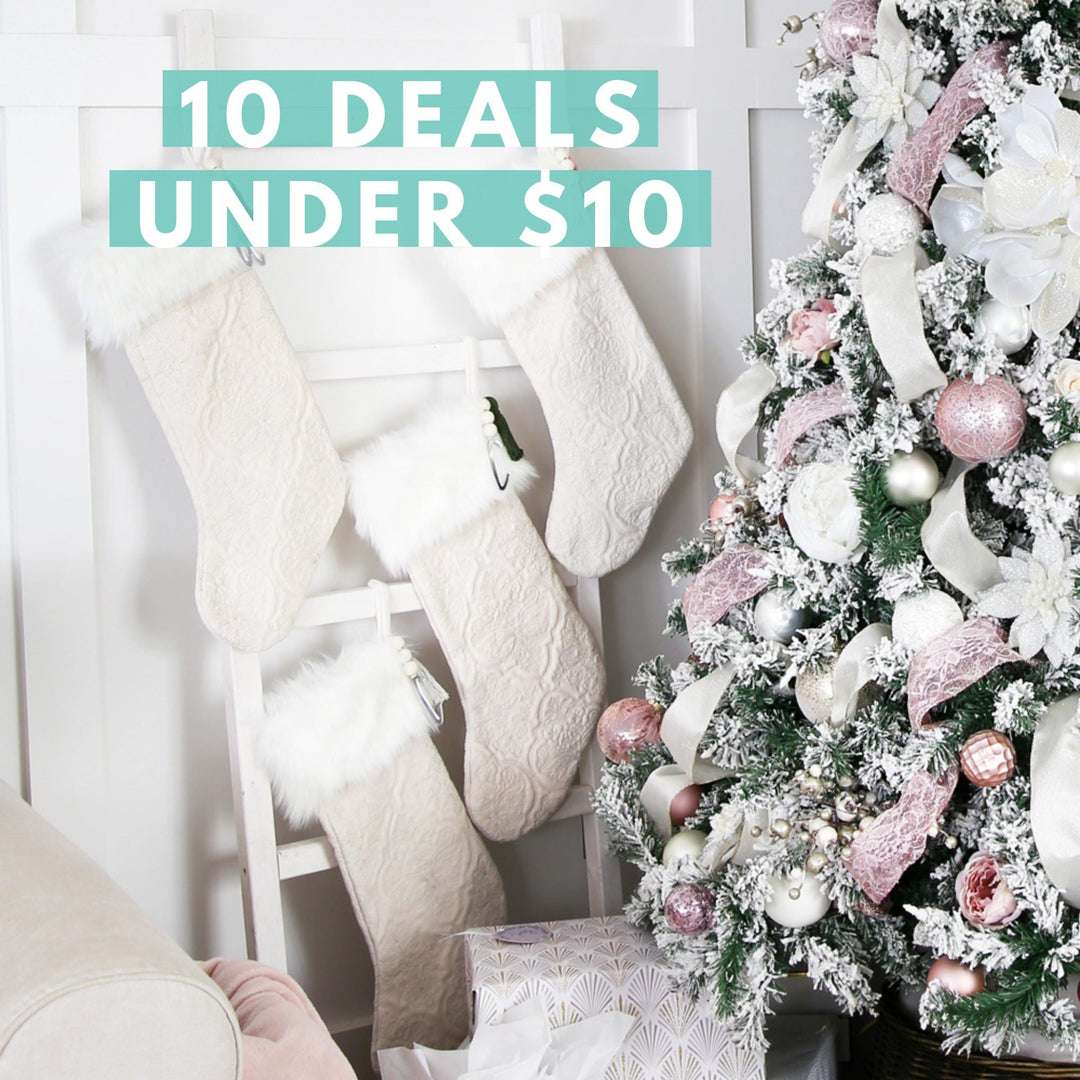 A white and pink decorated Christmas tree stands beside a ladder with three white stockings. Text over the image reads: "10 Deals Under $10.